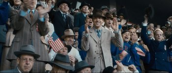 Movie still from “Race” (2016), directed by Stephen Hopkins – A group of men in suits and hats waving at the camera; Medium shot, Over the shoulder angle