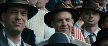 Movie still from “Race” (2016), directed by Stephen Hopkins – A person wearing a hat; Close Up shot, Over the shoulder angle