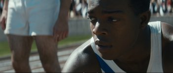 Movie still from “Race” (2016), directed by Stephen Hopkins – A young man's face as he sits on a track; Close Up shot, Over the shoulder angle