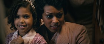 Movie still from “Race” (2016), directed by Stephen Hopkins – A woman and a little girl are looking at the camera; Close Up shot, Over the shoulder angle