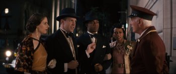 Movie still from “Race” (2016), directed by Stephen Hopkins – A group of men and women dressed up in suits and hats; Medium shot, Over the shoulder angle
