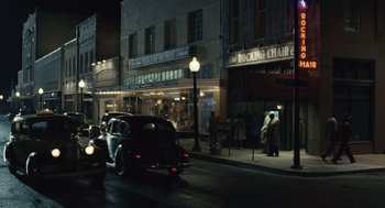 Movie still from “Ray” (2004), directed by Taylor Hackford – A car driving down a street next to a building at night; Extreme Wide shot, High angle
