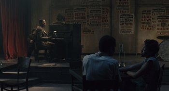 Movie still from “Ray” (2004), directed by Taylor Hackford – A man sitting in front of a piano in a dark room; Wide shot, Over the shoulder angle