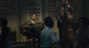 Movie still from “Ray” (2004), directed by Taylor Hackford – A man playing a guitar in front of a group of people; Wide shot, Over the shoulder angle