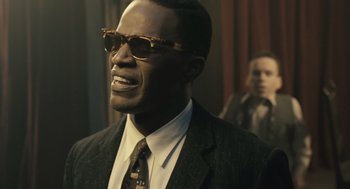 Movie still from “Ray” (2004), directed by Taylor Hackford – A man wearing a suit and sunglasses in front of a wall; Close Up shot, Over the shoulder angle