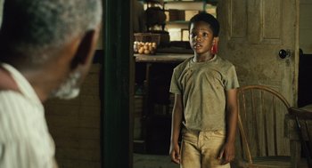 Movie still from “Ray” (2004), directed by Taylor Hackford – A young boy standing in a room looking at the camera; Medium shot, Over the shoulder angle