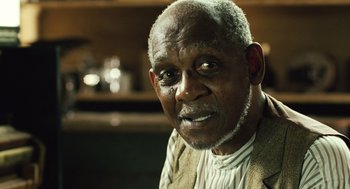 Movie still from “Ray” (2004), directed by Taylor Hackford – An older man with a beard and a white shirt; Close Up shot, Over the shoulder angle