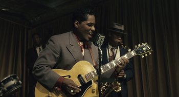 Movie still from “Ray” (2004), directed by Taylor Hackford – A man in a suit and tie playing a guitar and a man in a suit and tie playing a trumpet; Medium shot, Low angle
