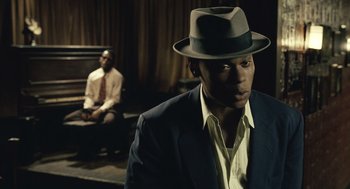 Movie still from “Ray” (2004), directed by Taylor Hackford – A man wearing a hat standing next to another man sitting on a bench; Close Up shot, Over the shoulder angle