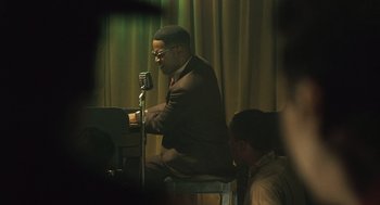 Movie still from “Ray” (2004), directed by Taylor Hackford – A man sitting at a piano with a microphone in front of him; Medium shot, Over the shoulder angle