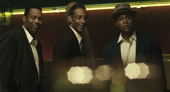 Movie still from “Ray” (2004), directed by Taylor Hackford – A group of men standing next to each other in a room; Medium shot, Low angle