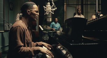 Movie still from “Ray” (2004), directed by Taylor Hackford – A man sitting at a piano in front of a microphone; Medium shot, Over the shoulder angle