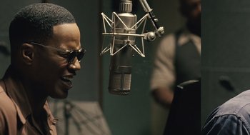 Movie still from “Ray” (2004), directed by Taylor Hackford – A person with a microphone in a room; Close Up shot, Over the shoulder angle