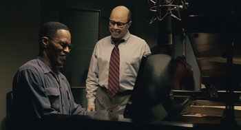 Movie still from “Ray” (2004), directed by Taylor Hackford – A man in a tie standing next to another man in a tie; Medium shot, Over the shoulder angle
