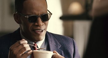 Movie still from “Ray” (2004), directed by Taylor Hackford – A man in a suit and sunglasses eating a cup of coffee; Close Up shot, Over the shoulder angle