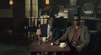 Movie still from “Ray” (2004), directed by Taylor Hackford – A couple of men sitting at a table with cups; Medium shot, High angle