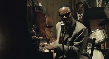 Movie still from “Ray” (2004), directed by Taylor Hackford – A man sitting at a piano with a microphone; Close Up shot, High angle