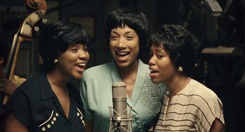 Movie still from “Ray” (2004), directed by Taylor Hackford – A group of three women singing into a microphone; Medium shot, High angle