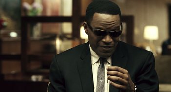 Movie still from “Ray” (2004), directed by Taylor Hackford – A man in a suit and sunglasses looking at his watch; Close Up shot, Over the shoulder angle