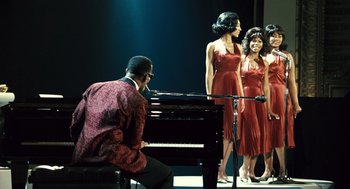 Movie still from “Ray” (2004), directed by Taylor Hackford – A man sitting at a piano next to three women; Wide shot, Over the shoulder angle