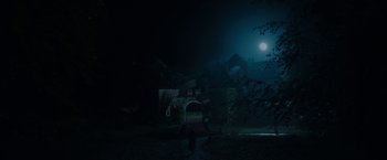 Movie still from “Rebecca” (2020), directed by Ben Wheatley – A person standing in front of a building in the dark; Extreme Wide shot, Low angle