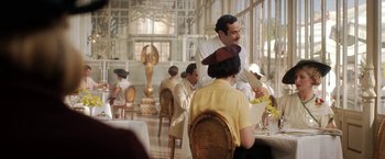 Movie still from “Rebecca” (2020), directed by Ben Wheatley – A man standing at a dining table with a woman; Medium shot, Over the shoulder angle