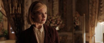 Movie still from “Rebecca” (2020), directed by Ben Wheatley – A woman with blonde hair wearing a brown jacket; Close Up shot, Over the shoulder angle