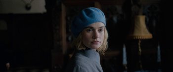 Movie still from “Rebecca” (2020), directed by Ben Wheatley – A woman wearing a blue hat is looking at the camera; Close Up shot, Over the shoulder angle
