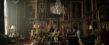 Movie still from “Rebecca” (2020), directed by Ben Wheatley – A room filled with lots of paintings and a chandelier; Wide shot, Low angle