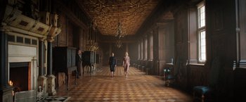 Movie still from “Rebecca” (2020), directed by Ben Wheatley – Two women are walking through a large room; Wide shot, Low angle