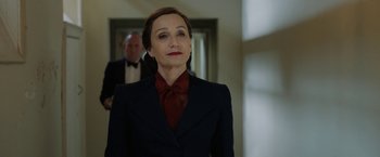 Movie still from “Rebecca” (2020), directed by Ben Wheatley – A woman wearing a suit and a red neck tie; Medium shot, Over the shoulder angle