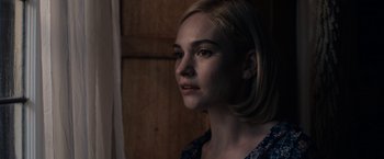 Movie still from “Rebecca” (2020), directed by Ben Wheatley – A woman with blonde hair is looking into the distance; Close Up shot, Over the shoulder angle