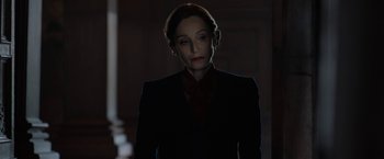 Movie still from “Rebecca” (2020), directed by Ben Wheatley – A woman wearing a suit and a red neck tie; Medium shot, Low angle