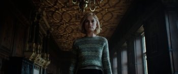 Movie still from “Rebecca” (2020), directed by Ben Wheatley – A woman standing in front of a chandelier in a darkened room; Medium shot, Low angle