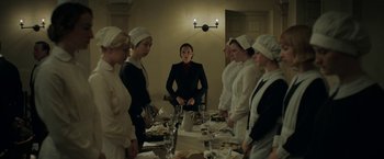 Movie still from “Rebecca” (2020), directed by Ben Wheatley – A group of women standing around a dinner table; Medium shot, Low angle