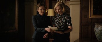 Movie still from “Rebecca” (2020), directed by Ben Wheatley – Two women standing next to each other holding a piece of paper; Medium shot, Over the shoulder angle