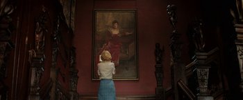 Movie still from “Rebecca” (2020), directed by Ben Wheatley – A woman standing in front of a large painting; Wide shot, Over the shoulder angle