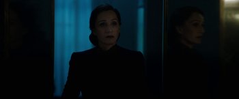 Movie still from “Rebecca” (2020), directed by Ben Wheatley – A woman standing in a dark room looking at the camera; Close Up shot, Over the shoulder angle