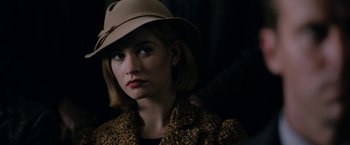 Movie still from “Rebecca” (2020), directed by Ben Wheatley – A woman wearing a tan hat and a brown jacket; Close Up shot, Over the shoulder angle