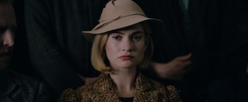 Movie still from “Rebecca” (2020), directed by Ben Wheatley – A woman wearing a tan hat and a jacket; Close Up shot, Over the shoulder angle