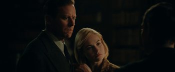 Movie still from “Rebecca” (2020), directed by Ben Wheatley – A man and a woman standing next to each other in a dark room; Close Up shot, Over the shoulder angle