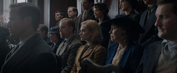Movie still from “Rebecca” (2020), directed by Ben Wheatley – A group of people sitting next to each other in a room; Medium shot, Over the shoulder angle