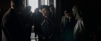 Movie still from “Rebecca” (2020), directed by Ben Wheatley – A group of people standing in a room; Medium shot, Over the shoulder angle