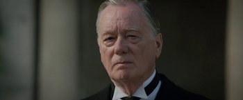 Movie still from “Rebecca” (2020), directed by Ben Wheatley – An older man wearing a suit and tie; Close Up shot, Low angle