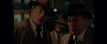 Movie still from “Rebecca” (2020), directed by Ben Wheatley – A group of men standing next to each other wearing hats; Close Up shot, Over the shoulder angle