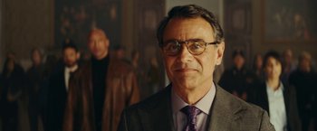 Movie still from “Red Notice” (2021), directed by Rawson Marshall Thurber – A person wearing glasses and a suit; Close Up shot, Over the shoulder angle