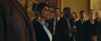 Movie still from “Red Notice” (2021), directed by Rawson Marshall Thurber – A group of people standing around a room; Medium shot, Over the shoulder angle