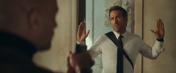 Movie still from “Red Notice” (2021), directed by Rawson Marshall Thurber – A man in a white shirt and a black neck tie; Close Up shot, Over the shoulder angle