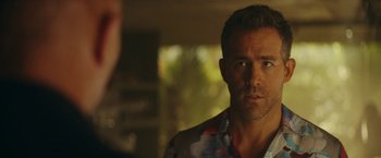 Movie still from “Red Notice” (2021), directed by Rawson Marshall Thurber – A person wearing a floral shirt; Close Up shot, Over the shoulder angle