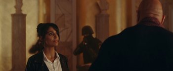 Movie still from “Red Notice” (2021), directed by Rawson Marshall Thurber – A woman standing in front of a man with a gun in a room; Medium shot, Over the shoulder angle